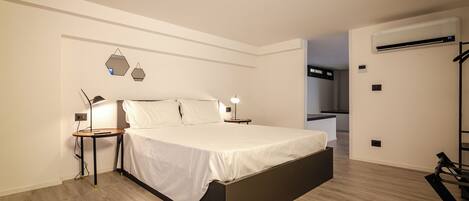 A modern bedroom with a bed, bedside tables, and a wall-mounted air conditioner.