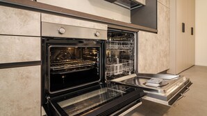 An open modern kitchen with a built-in oven and dishwasher, stainless steel appliances, and a minimalist design. - Saffi Lofts (Bologna)