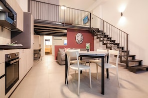 A modern kitchen with a dining area, a staircase, and a view of the living room.