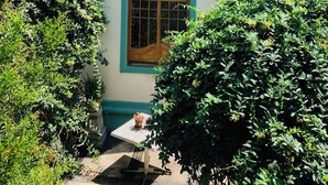 A building with a central window framed by green, a small table with a potted plant, and surrounding greenery. - On UNESCO property 3-bedroom quaint house surrounded by gardens in Barranco (Barranco)