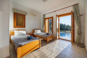 Ein Schlafzimmer mit zwei Holzbetten, einem Balkon mit Blick und einer Stehlampe.