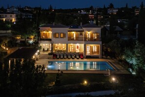 A multi-story house with a swimming pool, outdoor seating, and illuminated windows. - Villa 151 Luxury Villa - Private Pool and Tennis Court (Kouklia)