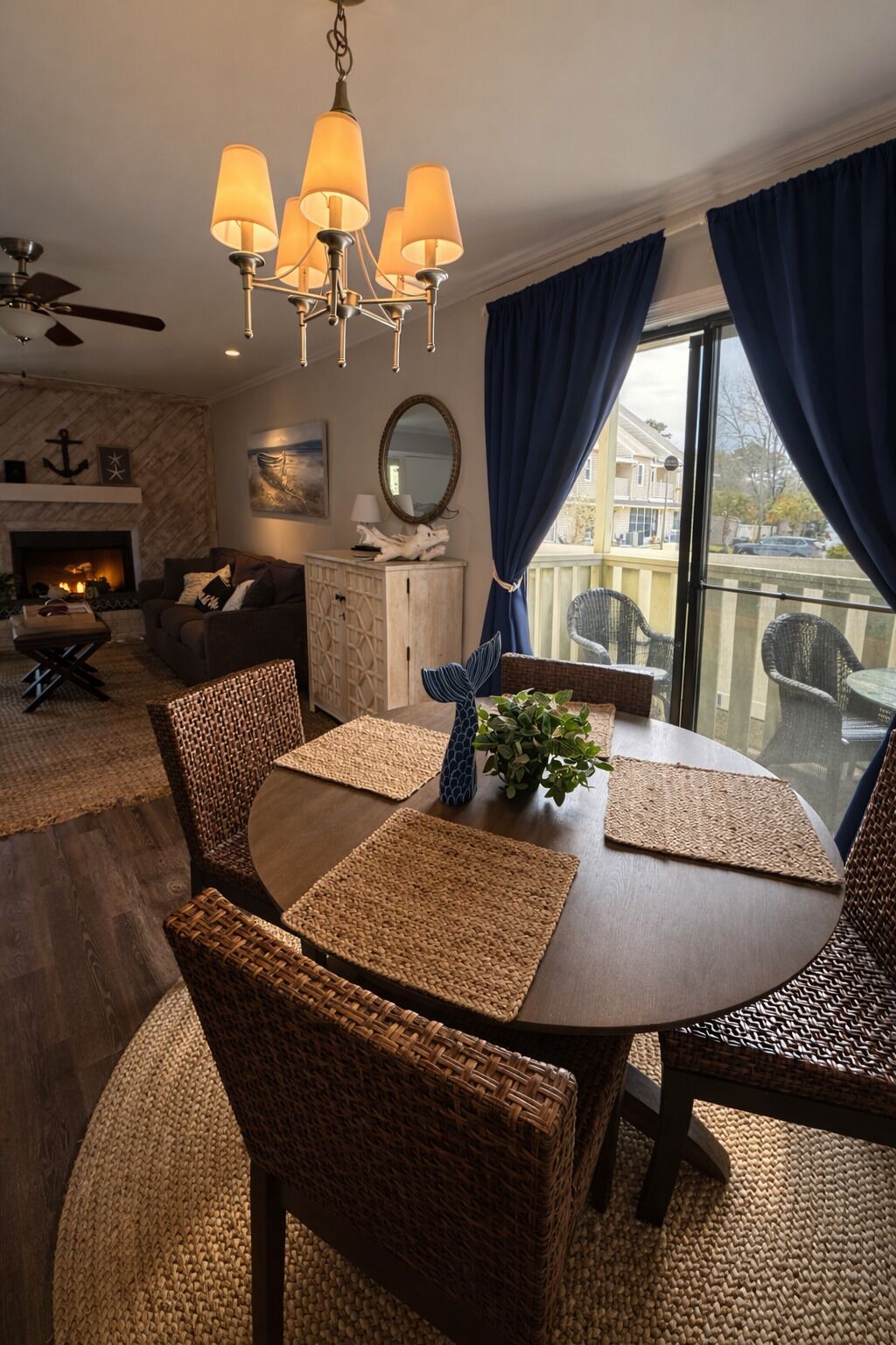 A dining area with a round table, woven chairs, and a chandelier.