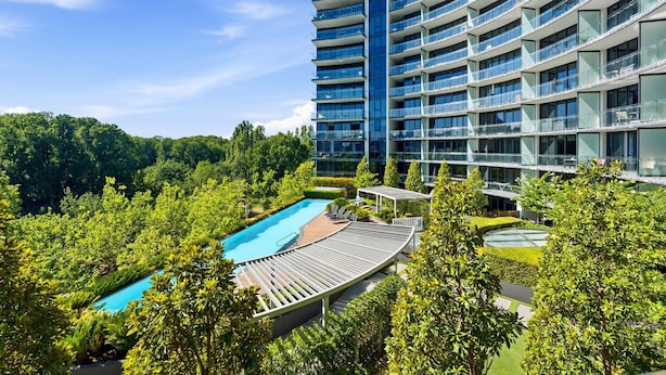 Et højt hotel med en swimmingpool omgivet af frodig vegetation.