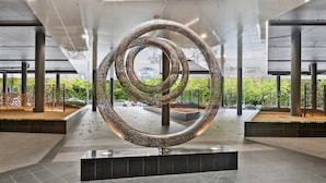 En moderne skulptur i en rummelig lobby med flisegulv og høje søjler.