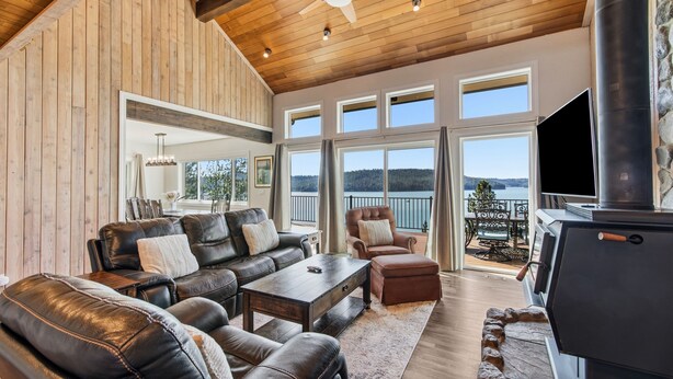 A spacious living room with leather sofas, a fireplace, and large windows offering a view of the outdoors.