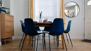 A dining area with a wooden table, four blue chairs, a wooden cabinet, a potted plant, and a mirror on the wall. - Modern, cozy, 2 bedroom, 1 bath home in Central Elkhart.  (Elkhart)