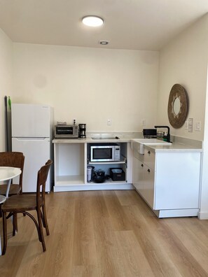 A compact kitchen with white cabinetry, a built-in microwave, and a small dining area with a table and chairs.