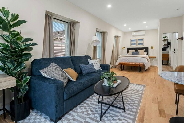A modern living room with a blue sofa, a coffee table, and a large plant.