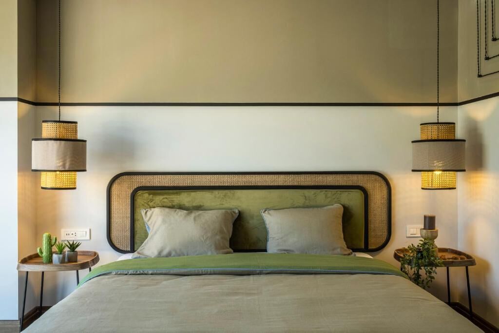 A bed with a green headboard, two bedside tables with lamps, and a small plant on each table.