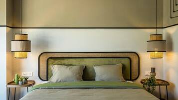 A bed with a green headboard, two bedside tables with lamps, and a small plant on each table.