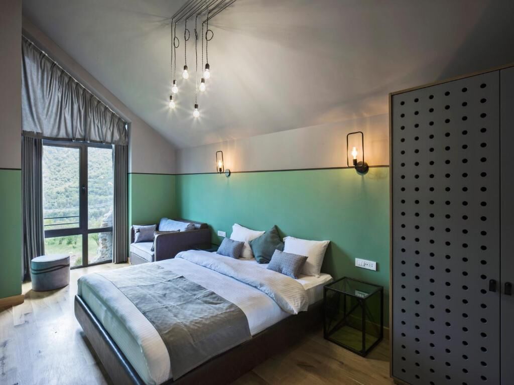 Une chambre à coucher avec un grand lit, une fenêtre avec des rideaux, une table de chevet et une armoire.