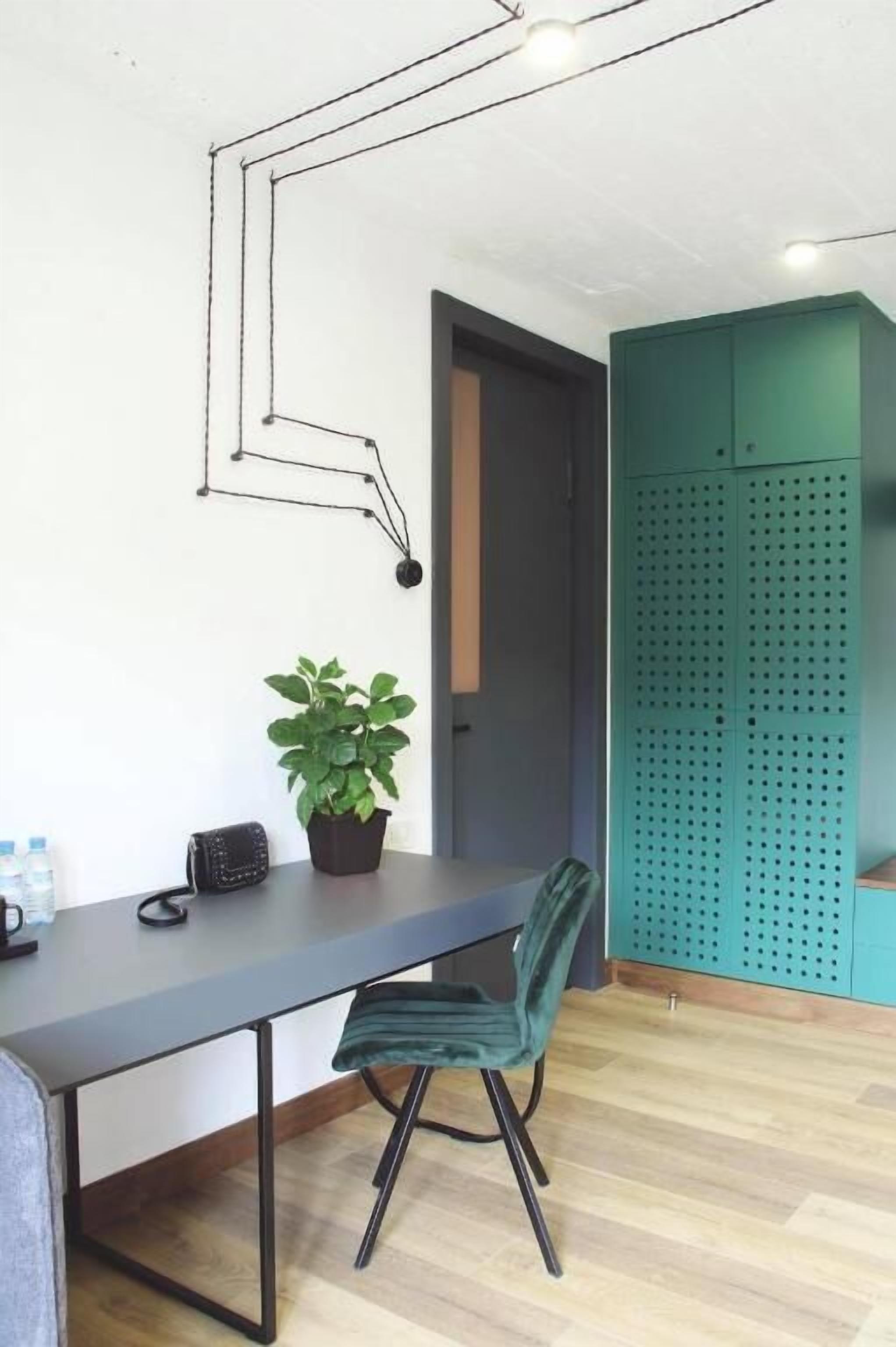 A room with a desk, chair, potted plant, and a green cabinet.