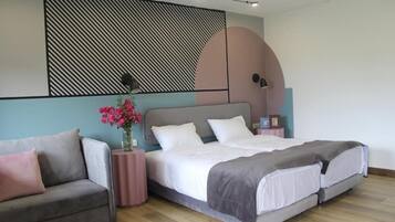 Un dormitorio con cama, sofá, luz empotrada y un panel decorativo.
