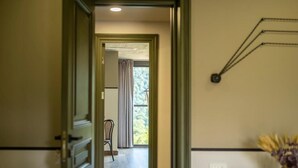 En inre hall med en dörr som leder till ett rum med utsikt över träd utanför.