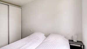 A minimalist bedroom with a bed, a nightstand, and a wardrobe. - Lessenaar 22 | 6 persoons chalet in Zennewijnen (Zennewijnen)