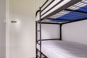 A bunk bed with a skylight, white walls, and a door. - Lessenaar 22 | 6 persoons chalet in Zennewijnen (Zennewijnen)