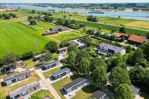 An aerial view of a residential area with houses, a river, and boats. - Lessenaar 22 | 6 persoons chalet in Zennewijnen (Zennewijnen)