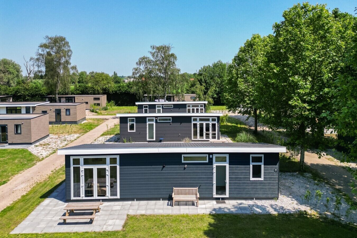 Un quartier résidentiel moderne composé de plusieurs maisons à deux étages, dotées de grandes fenêtres et d’un espace patio.