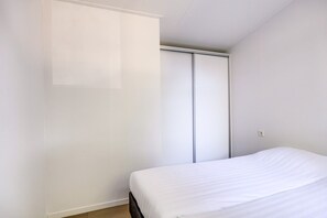 Ein Schlafzimmer mit einem Bett, einem Kleiderschrank und einer weißen Wand.
