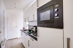 Eine moderne Küche mit integriertem Mikrowellenherd, einer Kaffeemaschine und einem Wasserkocher auf der Arbeitsfläche.