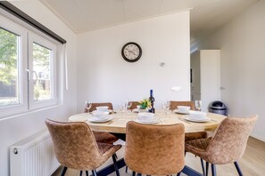 Ein Essbereich mit einem runden Tisch, gedeckt für vier Personen, mit weißen Tellern, Schüsseln und Weingläsern.