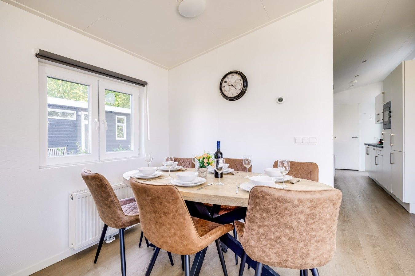 Un coin repas avec une table en bois, quatre chaises et une horloge au mur.