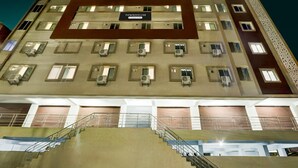 A multi-story building with a sign reading "TOWNHOUSE." It features multiple balconies, air conditioning units, and a staircase leading to the entrance. - Townhouse Kukatpally Formerly SV Royal (Hyderabad)