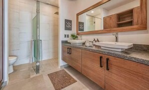 Un bagno con box doccia in vetro, due lavandini, mobili in legno e uno specchio grande.
