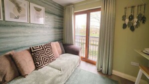 Una stanza con un divano, una finestra con tende, un muro decorato con quadri e una pianta sospesa.