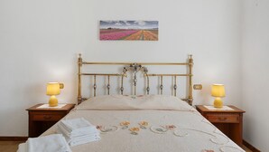 A bedroom with a bed, two bedside lamps, a wall-mounted painting, and a neatly folded set of towels. - Casa Teresa with Mountain View, Private Terrace, and Wi-Fi (Loppeglia)
