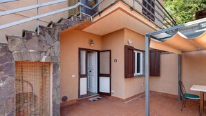 A residential property with a stone facade, a tiled patio, a door with a window, and a small table with a chair. - Casa Teresa with Mountain View, Private Terrace, and Wi-Fi (Loppeglia)