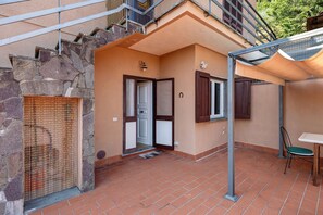 Ein Wohnhaus mit Steinverkleidung, einer gefliesten Terrasse, einer Tür mit Fenster und einem kleinen Tisch mit Stuhl.