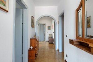Ein Korridor mit einem Holzkabinett, einem Spiegel und einer Tür zu einem anderen Raum.