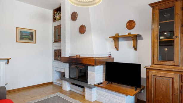 A living room with a fireplace, television, and wooden cabinet. - Casa Teresa with Mountain View, Private Terrace, and Wi-Fi (Loppeglia)