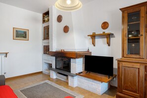 Ein Wohnzimmer mit Kamin, Fernseher und Holzkabinetten.