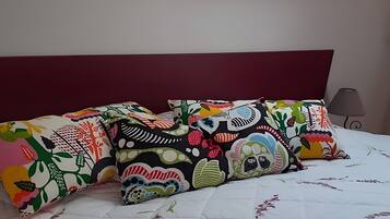 A bed with a floral quilt, a red headboard, and colorful pillows.