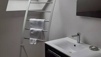 Une salle de bain moderne avec un puits de lumière, un lavabo blanc et un porte-serviettes.