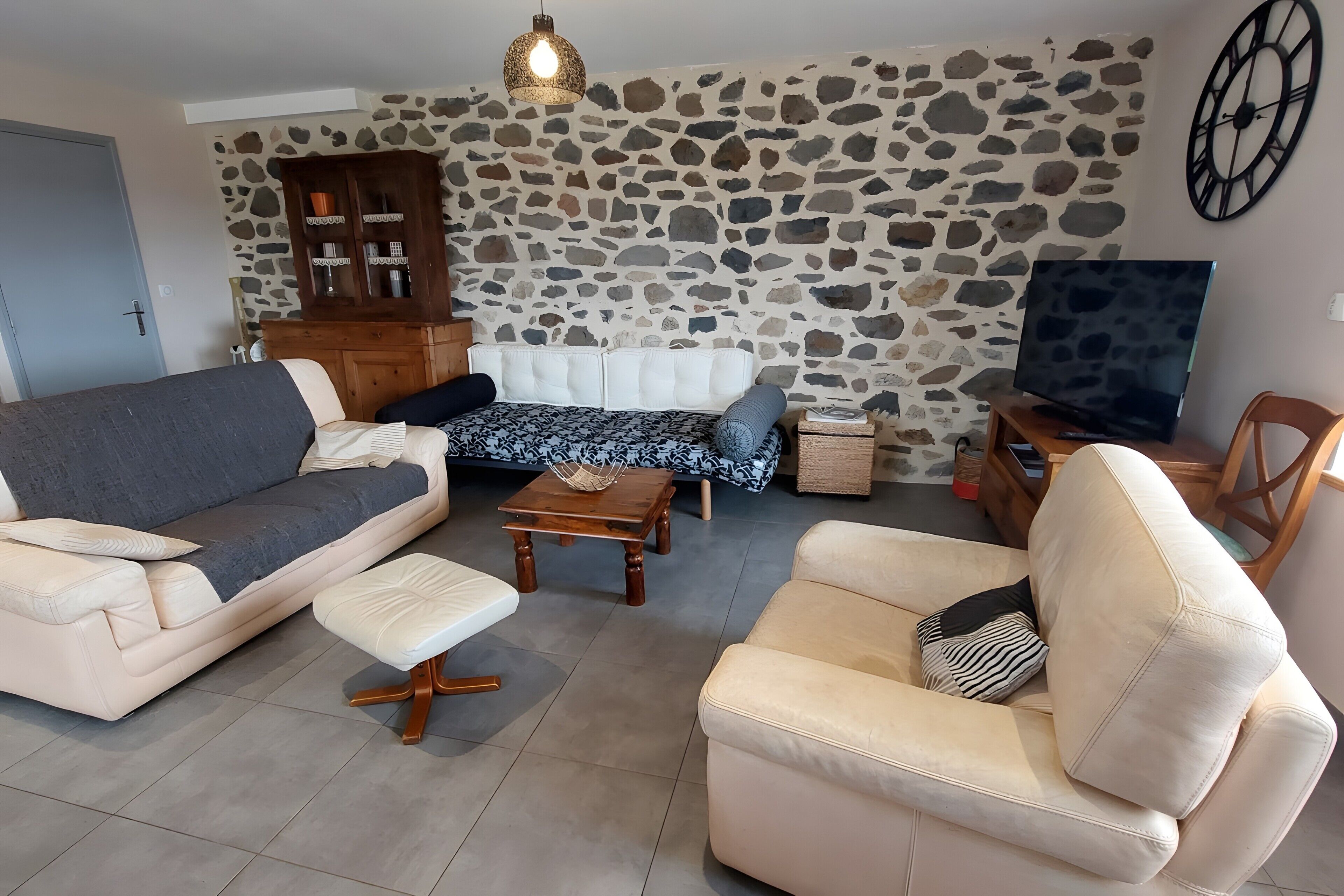 Ein Wohnzimmer mit Steinwand, einer Couch, einem Couchtisch und einem Fernseher.