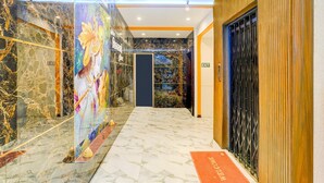 A hotel lobby with marble flooring, a mural, and an exit sign.