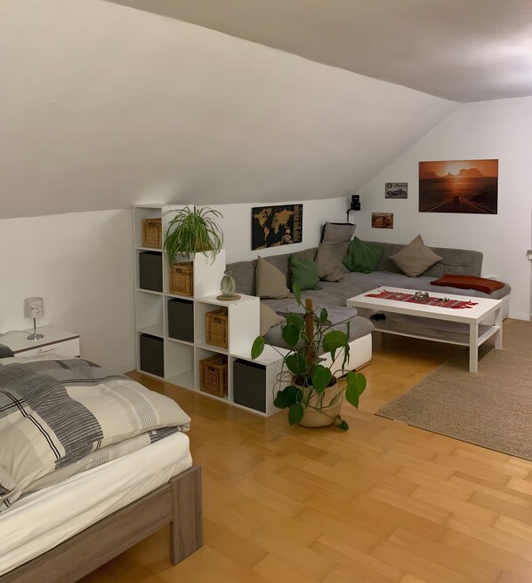 A modern living room with a sofa, coffee table, and a bed. - Worker's Apartment in Lehrte near Hannover – up to 2 Guests (Lehrte)