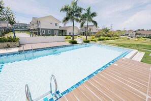 Una piscina con cubierta de madera, rodeada de casas y palmeras.
