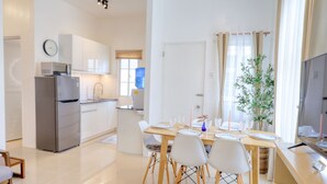 A modern kitchen with a refrigerator, microwave, and sink. There is a dining area with a table set for two, chairs, and a potted plant. - 3BR Guesthouse near Panglao • Pool • Bohol Tours (Dauis)