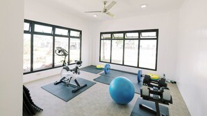 A gym with exercise equipment, large windows, and a ceiling fan. - 3BR Guesthouse near Panglao • Pool • Bohol Tours (Dauis)