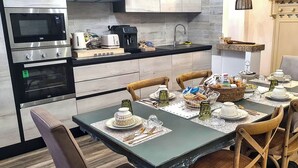A modern kitchen with a dining area set for a meal. - Nivalu Apartment (Olbia)