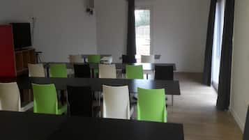 A conference room with tables and chairs, a television, and a door leading outside.