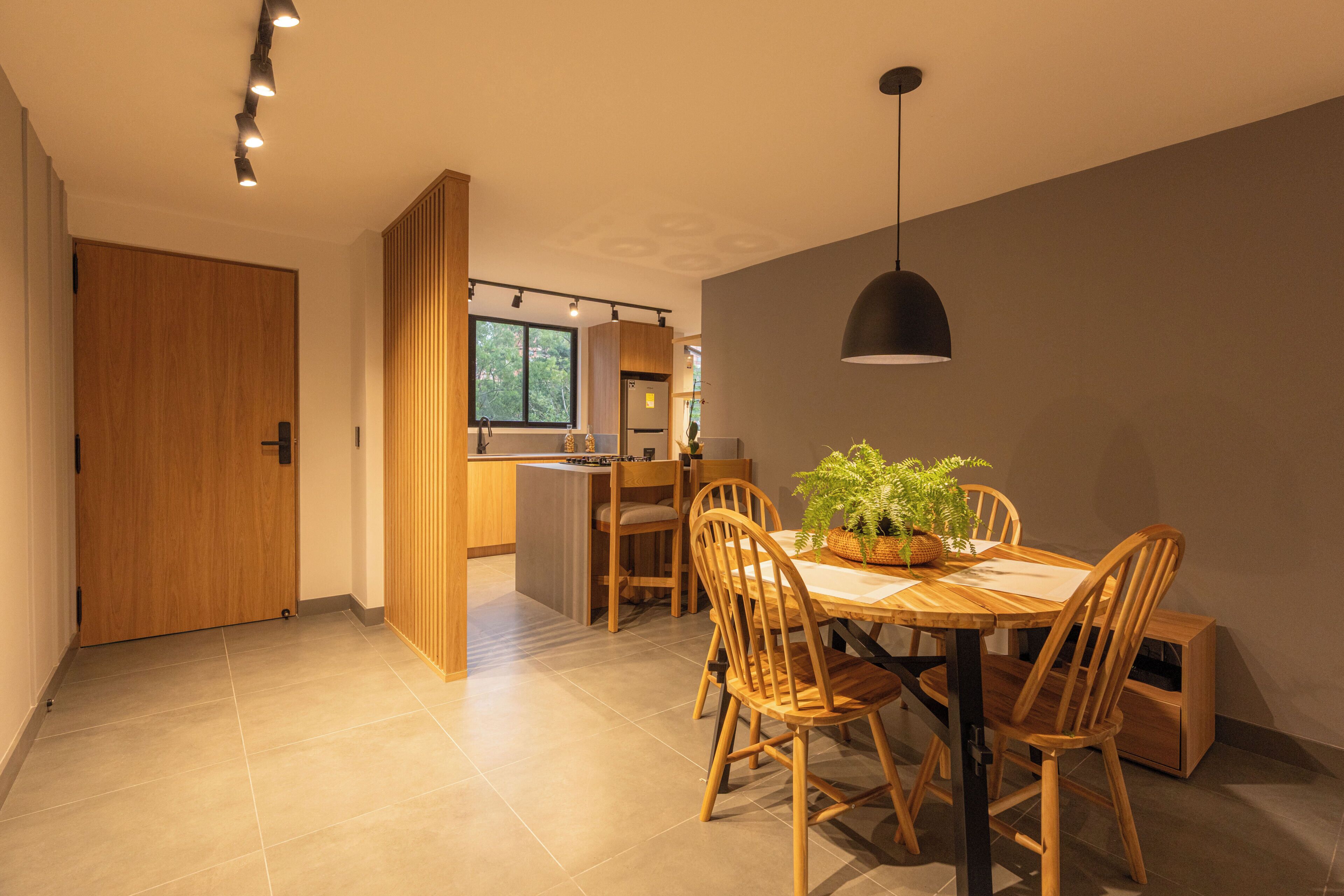 Una cocina moderna con armarios de madera, una mesa de comedor con sillas y una lámpara colgante.