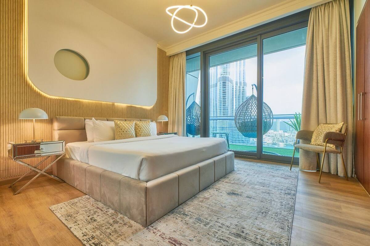 Un dormitorio moderno con una cama grande, una mesita de noche, una silla y vistas a la ciudad.