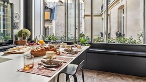 A breakfast setting with a long table, breakfast items, and a view of the city through large windows. - A 300m² Estate of Art, Elegance & Architectural Majesty:Blvd.de la Tour-Maubourg (Paris)
