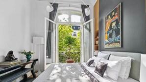 A bedroom with a bed, a desk, a chair, a potted plant, and a painting on the wall. - A 300m² Estate of Art, Elegance & Architectural Majesty:Blvd.de la Tour-Maubourg (Paris)
